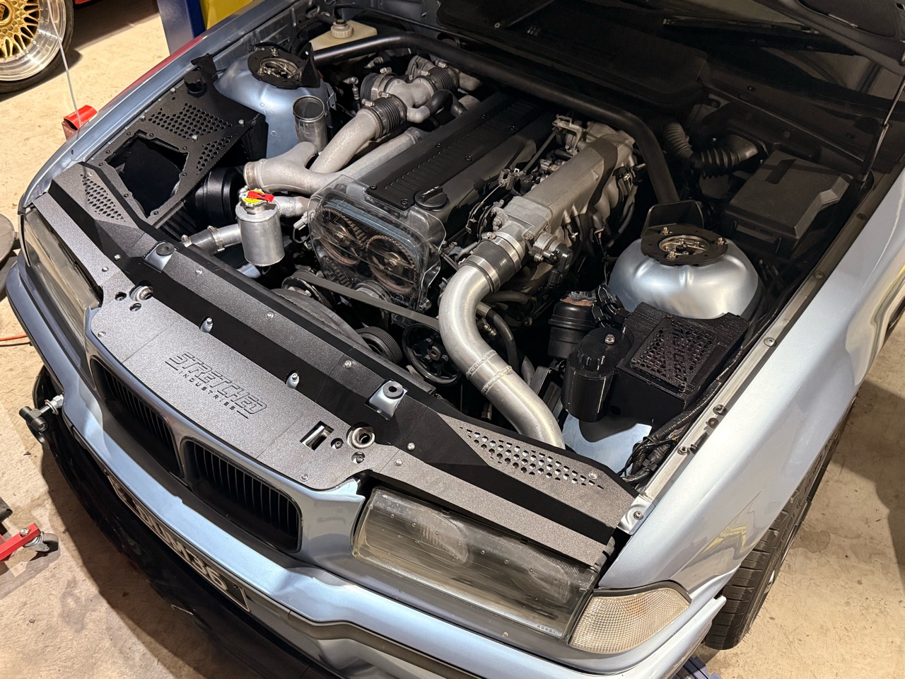Angled photograph of the Stretched Industries tucked radiator support cover in the E36 engine bay
